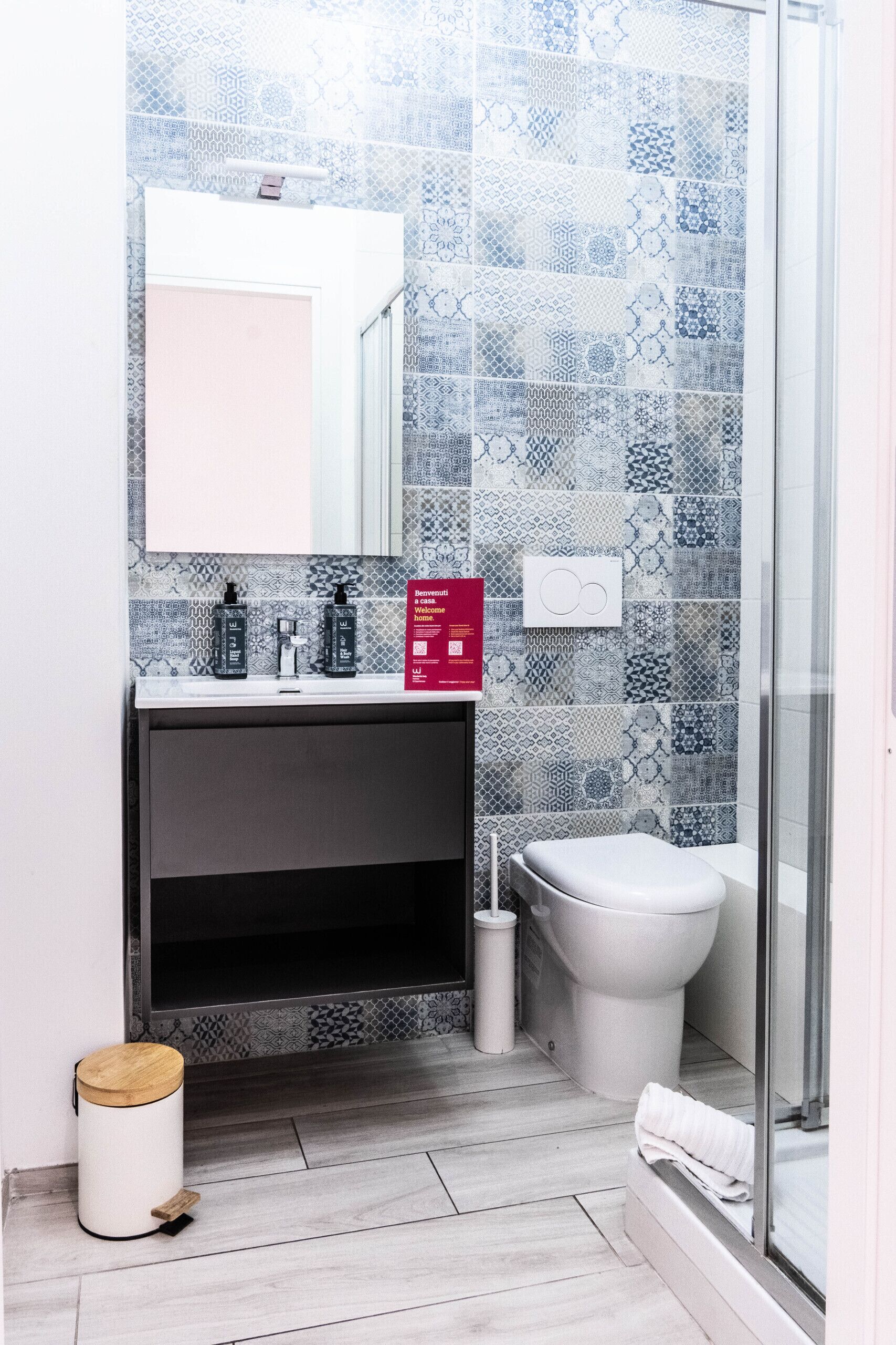 A bathroom with patterned tiles, a white sink, a toilet, and a shower area.