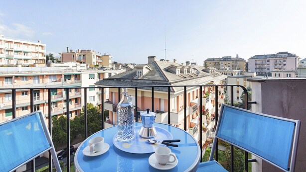 A balcony with a table set for two, a coffee pot, and a cup.