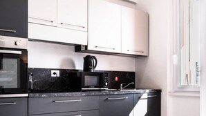 A modern kitchen with black and white cabinetry, a built-in microwave, and a coffee maker.
