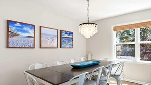 Un espace repas comprenant une table, des chaises et des œuvres d’art accrochées au mur.