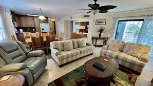 A spacious living room with a sofa, a recliner, a coffee table, and a dining area with a table and chairs.