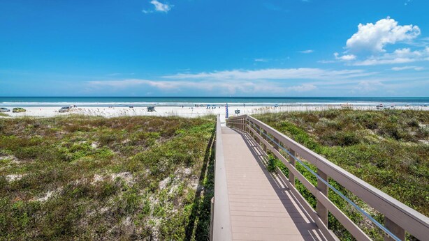 A boardwalk leading to a beach with dunes and a clear sky. - Beautifully upgraded Gold-rated unit, where style meets comfort. (Saint Augustine)