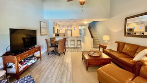 A living room with a television, sofa, and dining area. - Beautifully upgraded Gold-rated unit, where style meets comfort. (Saint Augustine)