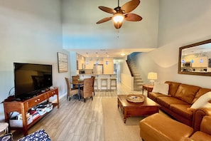 A living room with a television, sofa, and dining area. - Beautifully upgraded Gold-rated unit, where style meets comfort. (Saint Augustine)