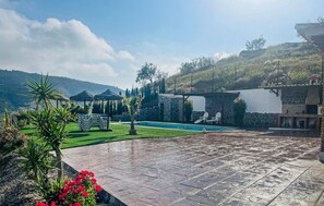 Uma área de piscina com um pátio de pedra, uma piscina pequena e um prédio de pedra com chaminé.