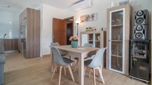 Une cuisine moderne avec des meubles en bois, une table à manger avec des chaises, un meuble encastré avec des portes en verre et un système de haut-parleurs intégré.