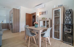 Uma cozinha moderna com armários de madeira, uma mesa de jantar com cadeiras, um armário embutido com portas de vidro e um sistema de som integrado.