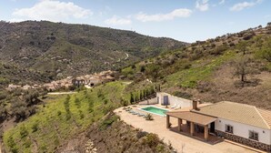 Une villa avec piscine, entourée de champs en terrasses et dominée par un paysage montagneux.