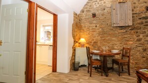 Um quarto aconchegante com parede de pedra, móveis de madeira e mesa de jantar posta para dois.