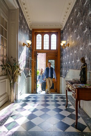A hallway with a checkered floor, a wooden door, and a statue on the right. - Hypocras: ideally located between Namur, Dinant, and Charleroi (Fosses-La-Ville)