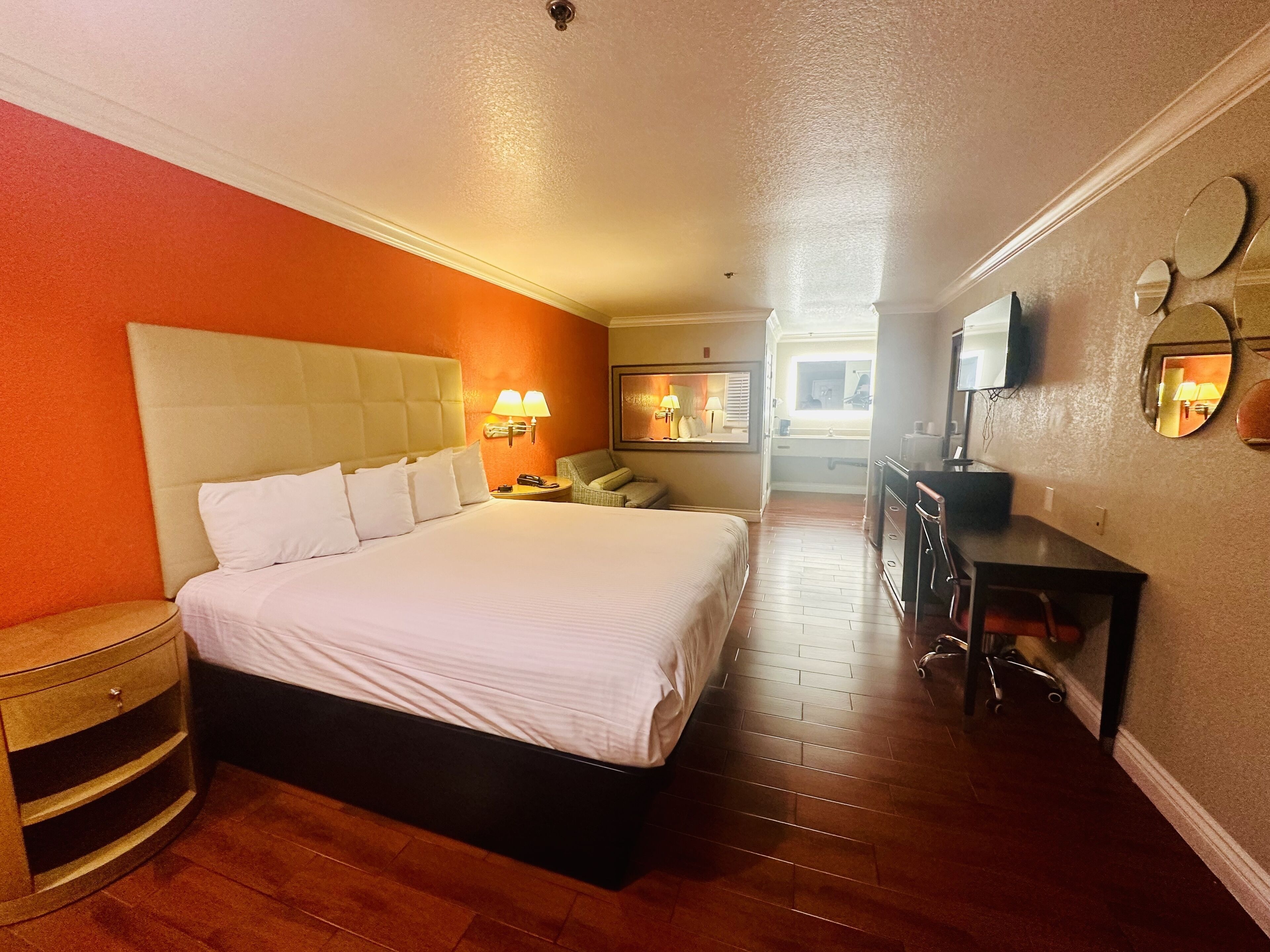 A hotel room with a large bed, a desk, a chair, and a television.