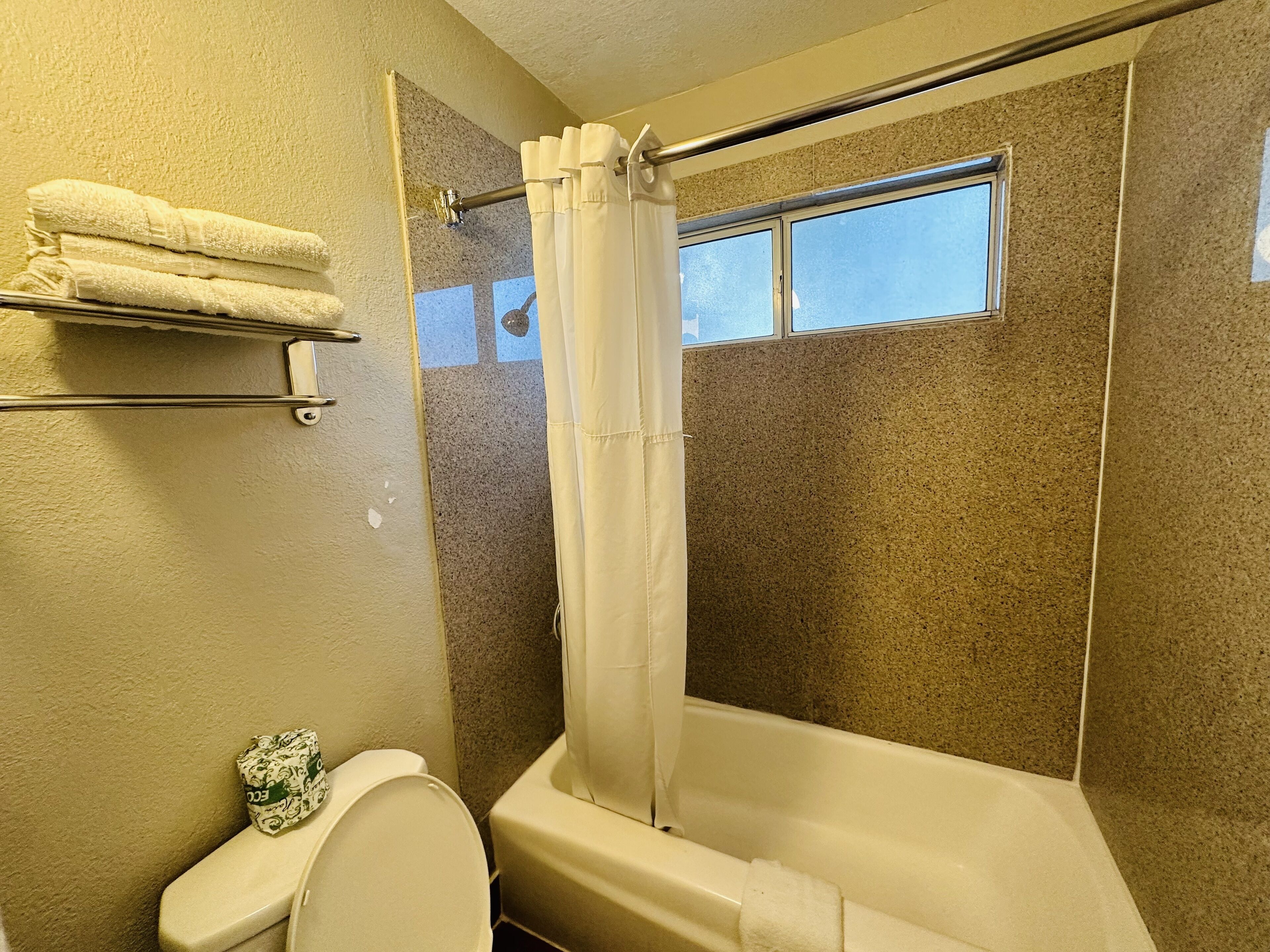 Un baño con ducha, inodoro y toallero.
