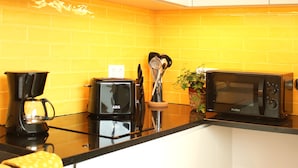 A kitchen with a black coffee maker, a toaster, and a microwave on a black countertop. - Villa Invicta II (Porto)
