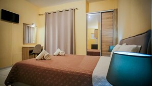A hotel room with a bed, a desk, a chair, a TV, and a mirror. - Yria ntn Studios (Zakynthos)
