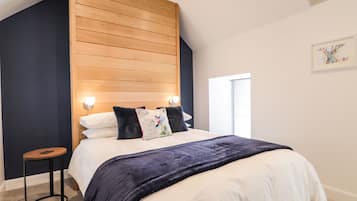 Une chambre à coucher avec un lit, des lampes de chevet, une petite table ronde et une fenêtre.