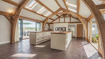 Una cocina amplia con una isla central, vigas de madera, tragaluces y vistas al exterior.