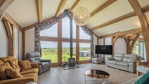 A spacious living room with large windows, a fireplace, and a flat-screen TV.