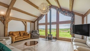 A spacious living room with a large window, a fireplace, and a television.