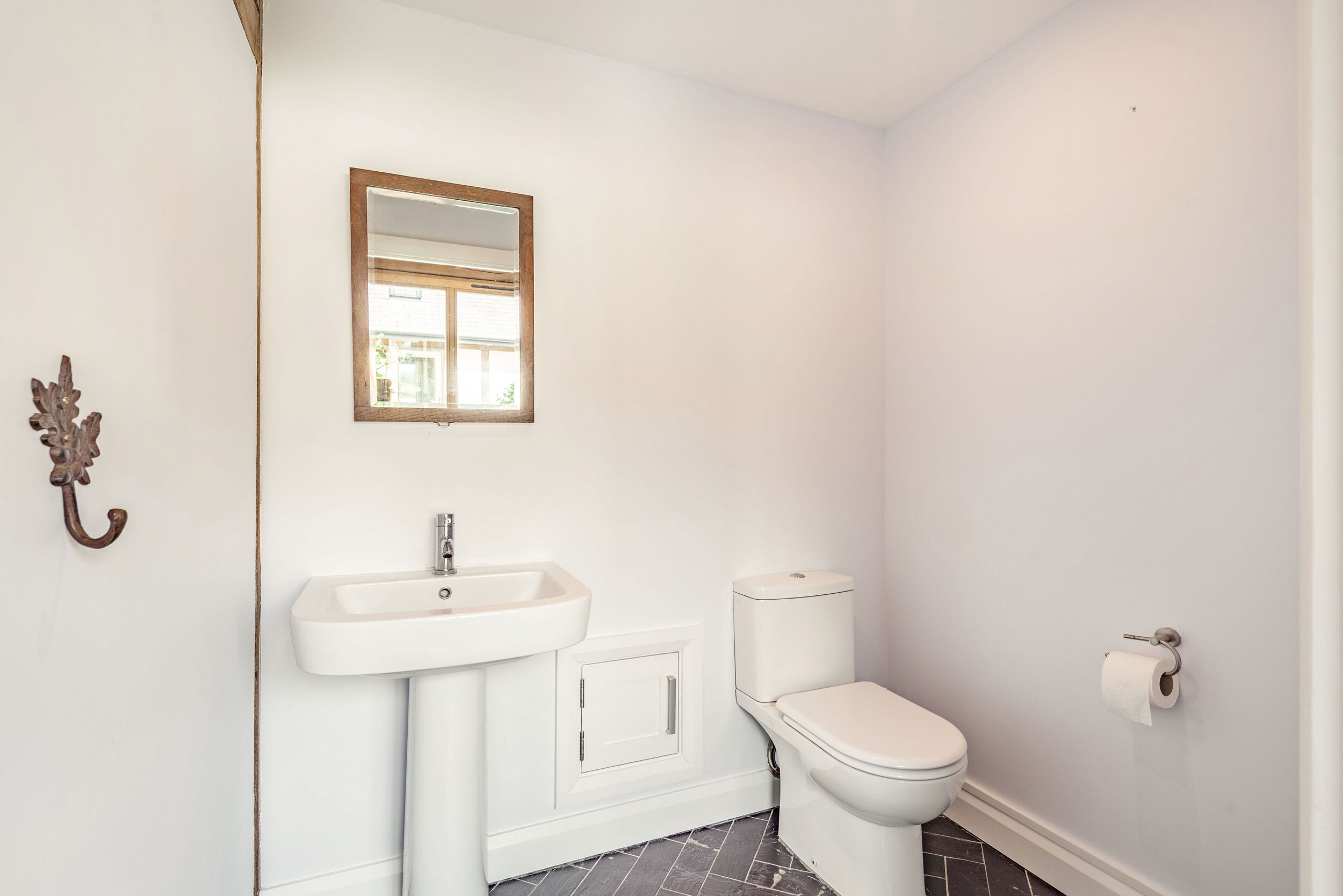 A bathroom with a white sink, toilet, and a mirror.