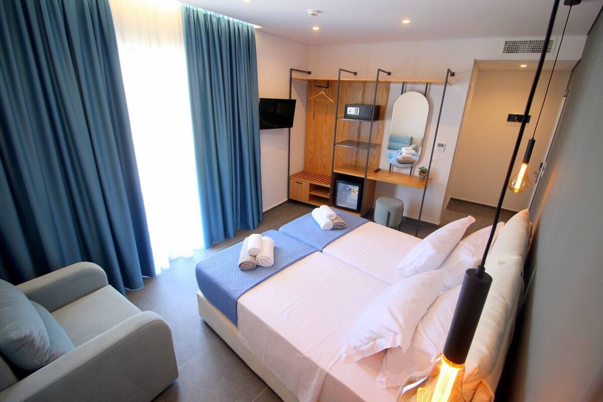 A hotel room with a bed, a desk, a chair, a TV, and a mirror.
