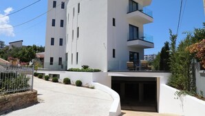 Un edifici modern de diversos pisos amb façana blanca, un logotip visible i un balcó al pis superior.