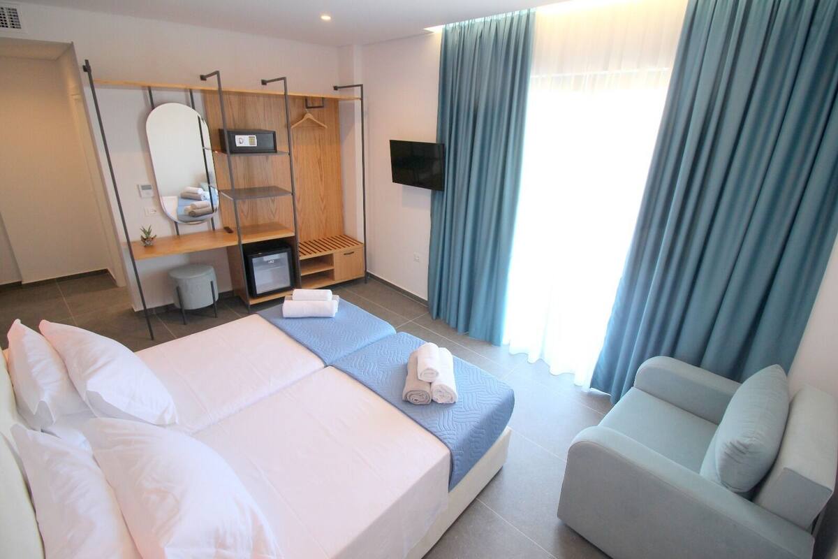 A hotel room with a bed, a desk, a chair, a TV, and a wardrobe.