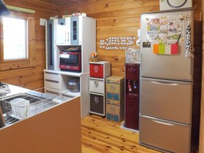 A compact kitchen with wooden walls, a microwave, a refrigerator, and a water dispenser.