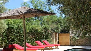 A swimming pool with red lounge chairs and a thatched umbrella. - Villa Mas du Château - Aircon- Private Pool (Villarzel-Cabardès)
