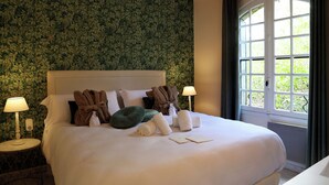 A neatly made bed with towels, pillows, and a robe, a bedside lamp, and a window with curtains. - Villa Mas du Château - Aircon- Private Pool (Villarzel-Cabardès)