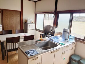 Une cuisine compacte équipée d’un évier, d’une cuisinière et d’un réfrigérateur. On y trouve une table à manger avec des chaises, ainsi qu’une fenêtre donnant sur l’extérieur.