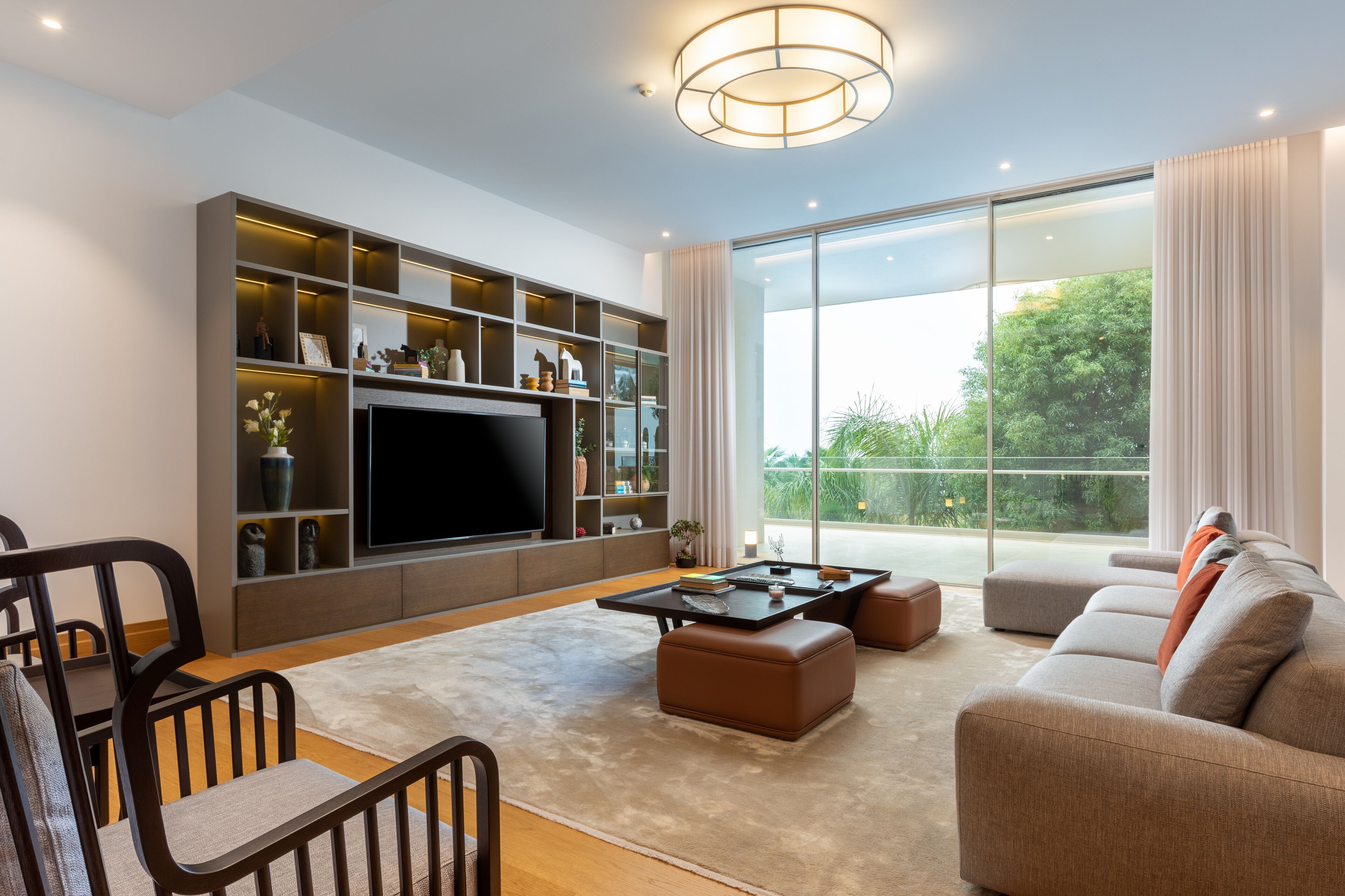 A modern living room with a large flat-screen TV, built-in shelves, a sofa, and a dining area.