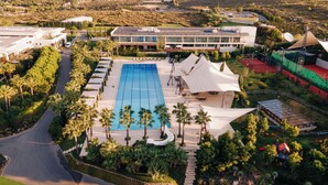 A resort with a large swimming pool, palm trees, and a view of the surrounding landscape. - Hiddenbay Teos Hotel Sigacik (Seferihisar)