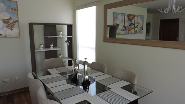 A dining area with a glass table, chairs, and a decorative mirror.