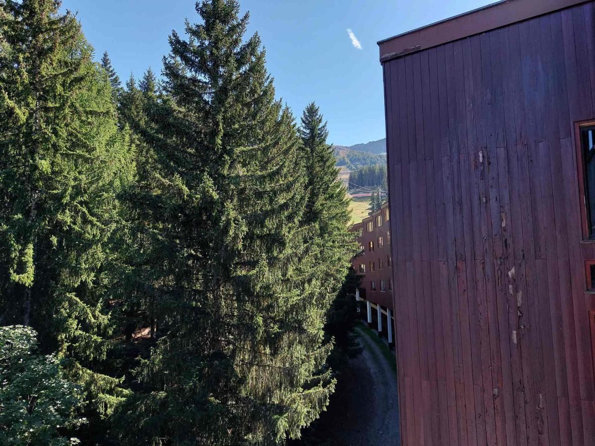 Ein Gebäude mit roter Fassade und Blick auf hohe, immergrüne Bäume.