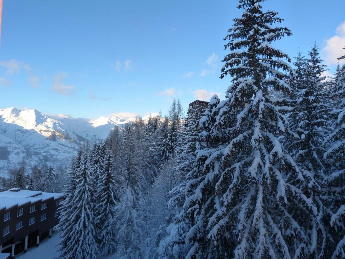 Eine verschneite Landschaft mit einem Gebäude im Vordergrund und Bergen im Hintergrund.