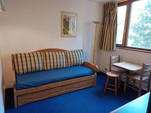 Um quarto aconchegante com um sofá de madeira, uma mesa pequena e uma cadeira.