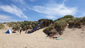 A sandy beach with a wooden slide and a tent. - Cozy cottage with fireplace, walking distance from the beach. (Nieuwvliet)