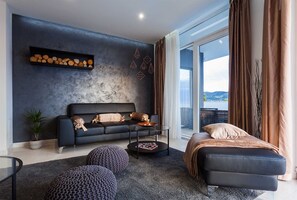 Ein modernes Wohnzimmer mit einer Couch, Hocker, einem Couchtisch und Blick ins Freie.