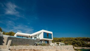 Ein modernes, zweistöckiges Haus mit Natursteinfassade und großen Fenstern, davor ein geparktes Auto.