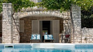 Ein Steinhaus mit einem Pool davor. Zwei Stühle stehen vor dem Gebäude.