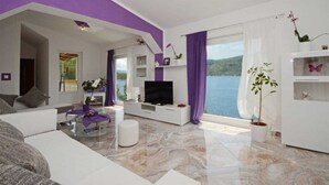 Un salon moderne doté d’un téléviseur, de sièges et offrant une vue sur la mer.