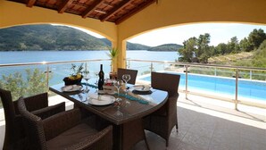 Un coin repas avec une table dressée pour quatre personnes, donnant sur un lac et des collines.
