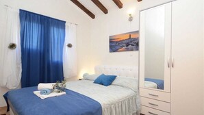 Une chambre à coucher avec un lit, une armoire, un tableau et une fenêtre avec des rideaux.