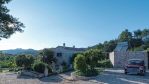 A stone house with a paved driveway and a parked car. - Holiday House  Gabrijel (Cara)