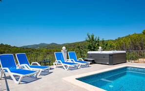 A pool area with lounge chairs and a hot tub, surrounded by a metal fence and greenery. - Holiday House  Gabrijel (Korcula)