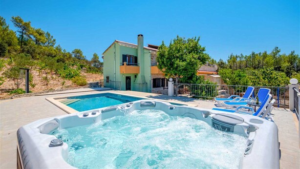 A swimming pool with a hot tub in the foreground, a house with a balcony in the background, and a clear blue sky. - Holiday House  Gabrijel (Cara)