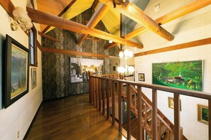 Stunning hallway with high ceilings, exposed beams, and beautiful artwork adorns the walls.