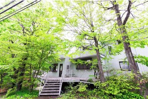 Staircase leads to a landing area in a two-story building surrounded by trees.