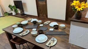 Une table à manger dressée avec différents plats, des couverts et un vase rempli de fleurs jaunes.