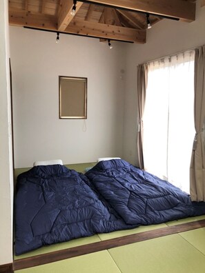 Une pièce avec un lit, un tableau encadré au mur et une fenêtre avec des rideaux.